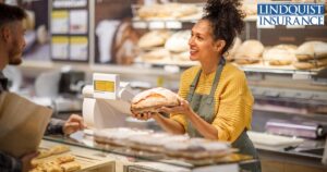 woman holding loaf of bread in bakery Lindquist Insurance